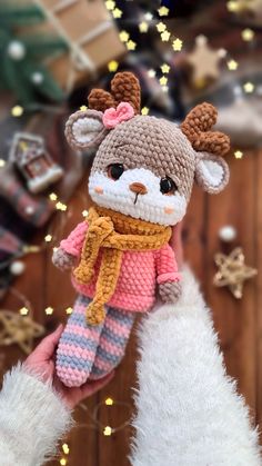 a hand holding a small stuffed animal wearing a scarf