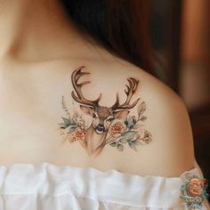 the back of a woman's shoulder with flowers and deer antlers on it