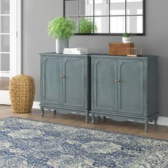 a room with a rug, mirror and blue cabinet