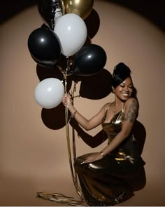 a woman in a gold dress holding balloons