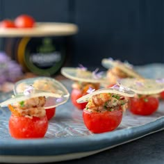 small appetizers with shrimp and tomatoes on a blue platter next to a bottle of wine