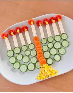 a white plate topped with cucumbers, carrots and pickles on skewers