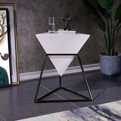 a white table with black legs and a painting on the wall