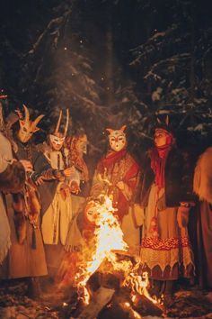 several people dressed in costumes standing around a campfire