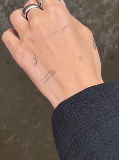 a person's hand with tattoos on it and a ring in their left hand