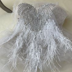 a white dress with silver sequins and feathers