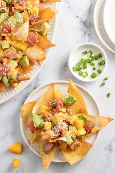 two plates filled with nachos on top of a table