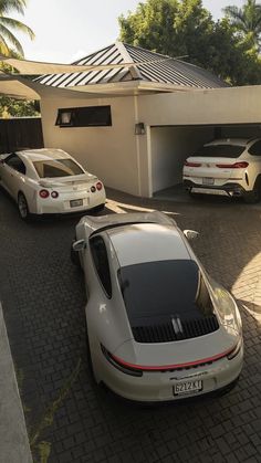 three cars parked in front of a house with two garages on the other side