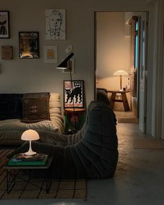 a person sitting on the floor in front of a couch with a lamp next to it