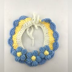 a crocheted blue and yellow flower wreath with white string hanging from the center