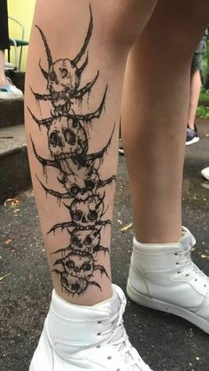 a person with a tattoo on their leg that has skulls and bones in the middle