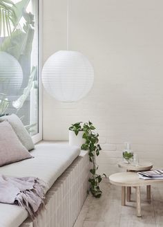 a living room filled with furniture next to a window covered in white paper lanterns hanging from the ceiling