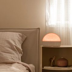 a lamp that is sitting on top of a nightstand next to a bed with white sheets