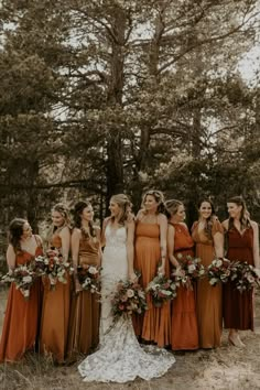 a group of women standing next to each other wearing dresses and holding bouquets in their hands