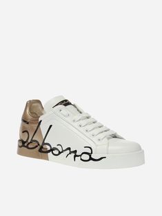 Step up your game with these elegant Dolce & Gabbana Two-Tone Portofino Sneakers. Boasting a white calf leather design, detailed black logo print and gold-tone accents, sneakers will keep you looking sharp. The comfortable rubber sole ensures you'll stay all day. Graffiti Logo, Black Logo, Leather Design, Gold Material, Step Up, Logo Print, Calf Leather