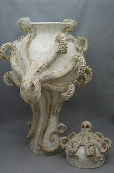 a white vase with an intricate design on the top and bottom, next to a smaller one