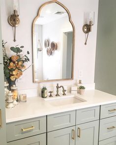 a bathroom sink with a mirror above it and flowers in the vase on the counter