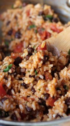 rice and beans are mixed together in a large bowl with a wooden spoon on the side