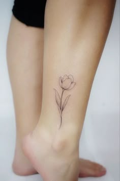 a woman's foot with a small flower tattoo on the left side of her leg