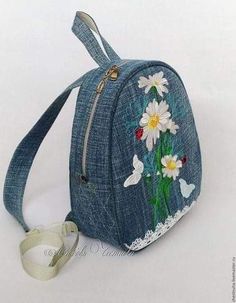 a denim bag with flowers and butterflies on it, sitting next to a white ribbon