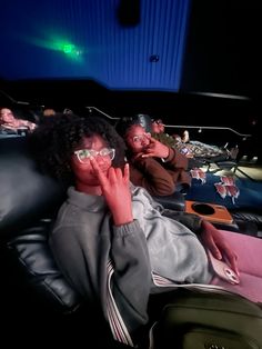 two people sitting in a movie theater with their hands up to their face and one person laying on the floor