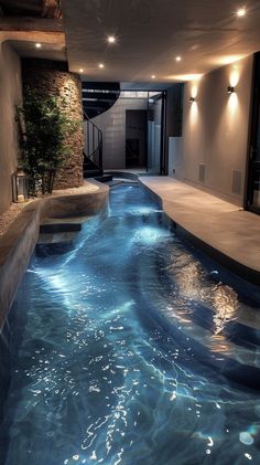 an indoor swimming pool with blue water and lights on the ceiling is lit by recessed lighting