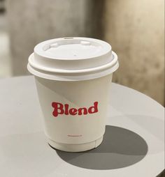 a coffee cup sitting on top of a table with the word blend written on it