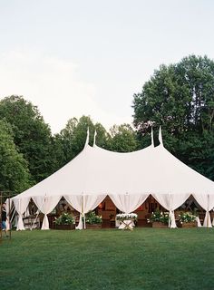 a large white tent set up in the middle of a field with tables and chairs