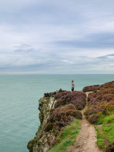 a man standing on top of a cliff next to the ocean