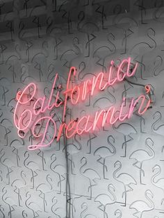 a neon sign that says california dreaming on the side of a wall with letters all over it