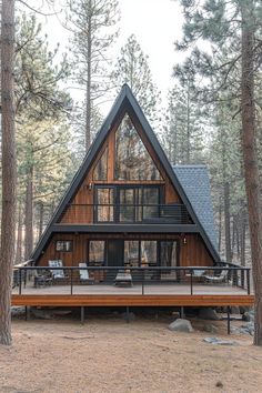 a - frame cabin in the woods with deck and chairs on the front porch, surrounded by pine trees