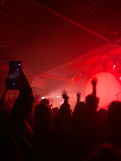 a group of people at a concert with their cell phones up in the air,