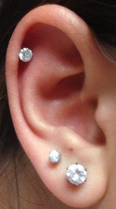 a woman's ear with three diamond studs