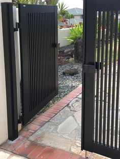 a black gate is open on a brick walkway