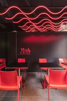 an empty restaurant with red chairs and black tables