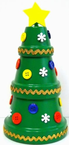 a green ceramic christmas tree with buttons and stars on it's top, against a white background