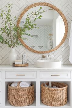 a white bathroom with baskets and a round mirror