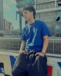 a young man sitting on top of a skateboard in front of a graffiti covered wall