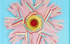 an image of a flower made out of strips of paper on a blue background with the center surrounded by red and yellow stripes