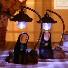 two figurines sitting on top of a table next to each other with lights