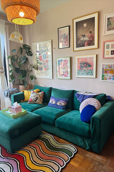 a living room with green couches and pictures on the wall above it's coffee table