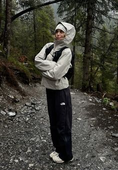 a man standing in the middle of a forest wearing a white hat and black pants