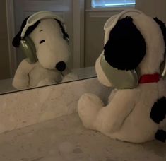 a stuffed dog sitting in front of a mirror with headphones on it's ears