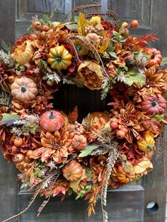 a wreath with pumpkins, leaves and other autumn flowers on a wooden door frame