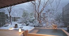 a hot tub sitting on top of a wooden deck next to a snow covered forest