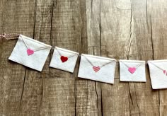 some paper hearts are hanging from a string on a wooden table with clothes pins attached to it