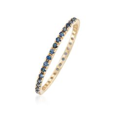 a yellow gold ring with blue sapphire stones on the inside and outside, set against a white background