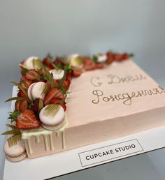 a cake decorated with strawberries and other toppings on top of a white box