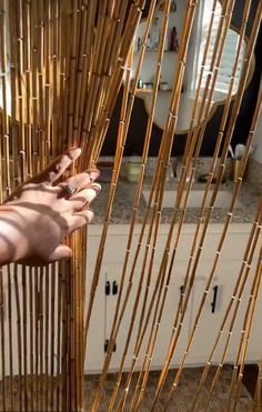 a person is holding up bamboo sticks in front of a bathroom mirror and vanity area