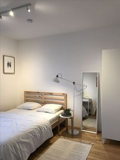 a bedroom with white walls and wooden floors